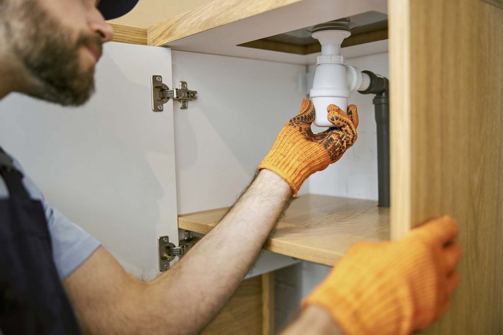 bearded-male-plumber-hands-fixing-pipe-in-kitchen-6AN38W8.jpg
